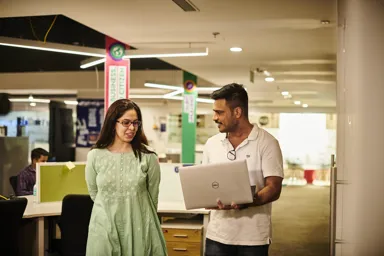 Two colleagues discussing work while looking at a laptop in an office setting