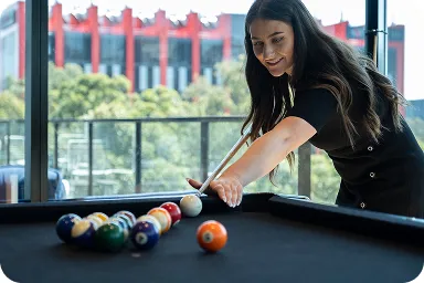 Una mujer jugando al billar, preparándose para intentar disparar a las pelotas