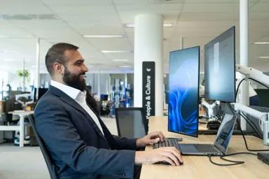 Man working at a desk with multiple computer monitors in an office setting